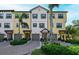 Front view of a contemporary yellow townhome with gray garage doors and lush landscaping at 5560 Cannes Cir # 3-106, Sarasota, FL 34231