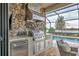 Luxury outdoor kitchen with stainless steel appliances and stonework, overlooking pool at 7014 Whittlebury Trl, Lakewood Ranch, FL 34202