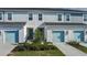 Three-unit townhome building with light gray siding, light blue garage doors, and landscaping at 8684 Canyon Creek Trl, Parrish, FL 34219