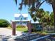 Charming light blue house with a wrap-around porch, brick pillars, and a gated entrance at 12334 Baypointe Ter, Cortez, FL 34215