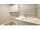 Laundry room with white cabinets, sink, and overhead shelving at 12681 Palatka Dr, Venice, FL 34293