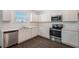 Modern white kitchen with stainless steel appliances and laminate flooring at 13009 Cedar Elm Lane, Parrish, FL 34219