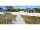 Beachfront property with sandy walkway and blue picnic shelters at 2110 Harbourside Dr # 522, Longboat Key, FL 34228