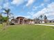 Single-story home with a red door, landscaped lawn, and palm trees at 25067 Palisade Rd, Punta Gorda, FL 33983