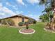 Landscaped yard with a tan house exterior and palm trees at 25067 Palisade Rd, Punta Gorda, FL 33983