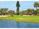 Scenic golf course with palm trees, water features, and golf carts at 548 Ketch Ln, Longboat Key, FL 34228