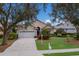 Tan one-story house with a white garage door and lush landscaping at 6726 Virginia Xing, University Park, FL 34201