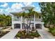Two-story house with a light yellow exterior, palm trees, and a landscaped yard at 727 Holly Rd, Anna Maria, FL 34216