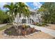 Two-story house with light-yellow siding, palm trees, and a landscaped front yard at 727 Holly Rd, Anna Maria, FL 34216