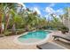 Freeform swimming pool with a patio, lounge chairs, and lush landscaping at 727 Holly Rd, Anna Maria, FL 34216