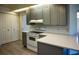 Modern kitchen featuring gray cabinets, white appliances, and quartz countertops at 8282 Parkside Dr, Englewood, FL 34224