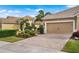 Home's exterior features a tan facade, two-car garage, and a brick-paved driveway at 12199 Sebring Ln, Venice, FL 34293