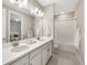 Modern bathroom with double vanity, a shower, and white cabinets at 16127 Fortezza Dr, Bradenton, FL 34211