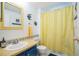 Simple bathroom with blue vanity, yellow shower curtain, and tiled accents at 2107 Palma Sola Blvd # 59, Bradenton, FL 34209
