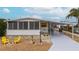 White mobile home with covered carport, yellow chairs, and landscaped yard at 2107 Palma Sola Blvd # 59, Bradenton, FL 34209