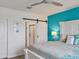 Main bedroom with white bed frame, teal accent wall, and barn door to en suite bathroom at 3206 Hilltop Cir, Bradenton, FL 34211