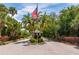 Charming community entrance with an American flag and towering palms along a tree lined street at 3663 Muirfield Dr # 4B, Sarasota, FL 34238