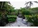 Lush backyard with tropical landscaping and stone pathways at 3947 Country View Dr, Sarasota, FL 34233