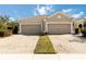 Tan two-car garage home with a paved driveway and landscaping at 5050 Maymont Park, Bradenton, FL 34203