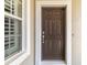 Dark brown front door with a white frame and adjacent window at 5050 Maymont Park, Bradenton, FL 34203