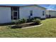 Rear view of manufactured home with small trees and lawn at 763 Lakeside Dr, North Port, FL 34287