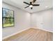Bright bedroom with wood-look floors, ceiling fan, and window at 3850 Skyway Ave, North Port, FL 34288
