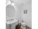 Small bathroom with pedestal sink, toilet, and round mirror at 650 Golden Gate Pt # 401, Sarasota, FL 34236