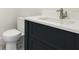 Close up on a modern white marble countertop with a sink and faucet over a navy blue vanity and toilet at 8376 Sea Glass Ct, Sarasota, FL 34240