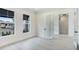 Bright bedroom with light gray floors, two windows with black awnings, and a glass door at 8376 Sea Glass Ct, Sarasota, FL 34240