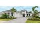 Beautiful home featuring white stucco, black window awnings, two-car garage, paved driveway and manicured landscaping at 8376 Sea Glass Ct, Sarasota, FL 34240