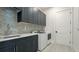 Modern laundry room features gray cabinetry, marble countertops, stainless steel sink and new washer and dryer at 8376 Sea Glass Ct, Sarasota, FL 34240