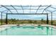 An inviting screened-in pool and spa offer beautiful views of the green landscape and blue sky at 8376 Sea Glass Ct, Sarasota, FL 34240