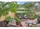 Brick patio with seating area, lush landscaping, and a green umbrella at 430 Beach Park Blvd, Venice, FL 34285