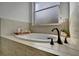 Bathroom with a freestanding soaking tub, neutral tile, and window at 5125 Tidewater Preserve Blvd, Bradenton, FL 34208