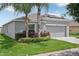 One-story home with gray siding, solar panels, and a two-car garage. Features a landscaped yard with palm trees and lush greenery at 208 Cascade Bend Dr, Ruskin, FL 33570