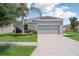 Charming one-story home with gray siding, solar panels, and a two-car garage. Features well-maintained landscaping and palm trees at 208 Cascade Bend Dr, Ruskin, FL 33570