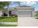 One-story home with gray siding, solar panels, and a two-car garage. Lush landscaping with palm trees and manicured lawn at 208 Cascade Bend Dr, Ruskin, FL 33570