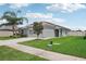 One-story home with gray siding, solar panels, and a two-car garage. Features a spacious yard with mature trees and lush grass at 208 Cascade Bend Dr, Ruskin, FL 33570