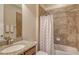 Bathroom with a granite countertop, white sink, and a shower-tub combo with tiled walls at 6630 Horned Owl Pl, Sarasota, FL 34241