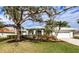 Single-story home with a white exterior, lush landscaping, and a two-car garage at 8303 Deerbrook Cir, Sarasota, FL 34238