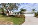 Single-story home with a white exterior, landscaped yard, and a two-car garage at 8303 Deerbrook Cir, Sarasota, FL 34238