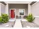 Front porch with red door, wicker chairs, and a stone pathway at 12811 Wheatgrass Ct, Parrish, FL 34219