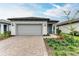 Single-story home with gray garage door, landscaping, and paver driveway at 6273 Winding Pine Dr, Nokomis, FL 34275