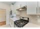 Modern kitchen with white cabinets, stainless steel appliances, and herringbone tile backsplash at 6273 Winding Pine Dr, Nokomis, FL 34275