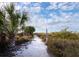 Sandy path to beach lined with vegetation and signage at 711 Russell St, Longboat Key, FL 34228