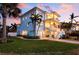 Coastal home with balconies and stairs leading to the front door, lit by the sunset and tropical trees at 718 Key Royale Dr, Holmes Beach, FL 34217