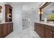 Elegant main bathroom with double sink vanity, marble floors, glass shower, and custom cabinets at 718 Key Royale Dr, Holmes Beach, FL 34217