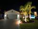 Night view of a luxury home with palm trees and landscape lighting at 10916 Copperlefe Dr, Bradenton, FL 34212