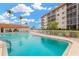 Community pool with blue water and a charming building, surrounded by inviting lounge chairs and lush palm trees at 1600 1St W Ave # 304A, Bradenton, FL 34205