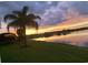 Sunset view over lake, lush grass, and palm tree at 2536 Marton Oak Blvd, North Port, FL 34289